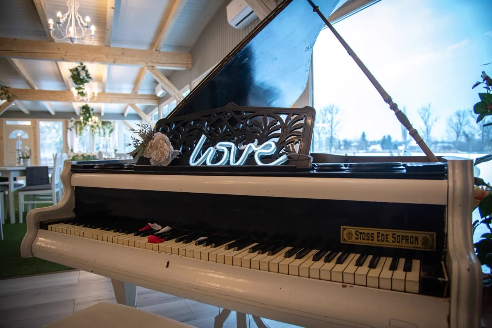 Fehér zongora love neonfelirattal, mögötte a havas táj az Éden Lounge termében