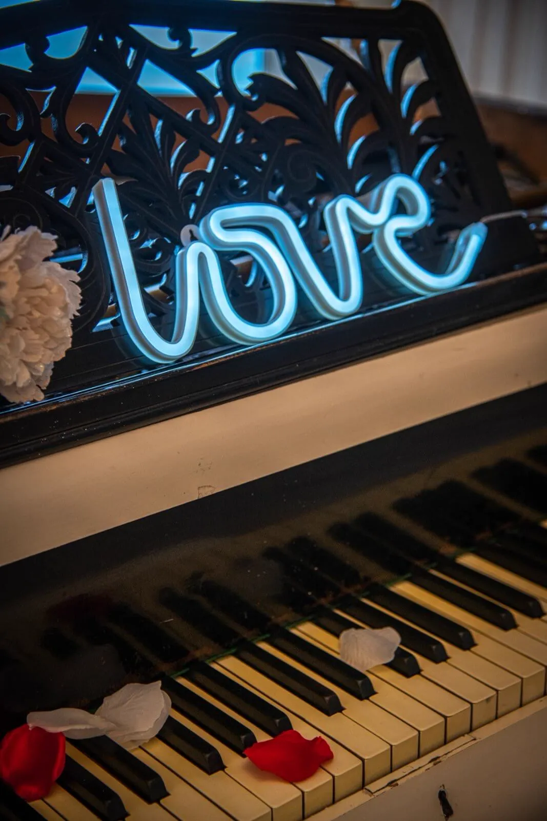 Love neonfelirat a zongorán, rózsaszirmokkal a billentyűkön